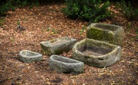 A GROUP OF FIVE VARIOUS CARVED STONE TROUGHS OR BASINS