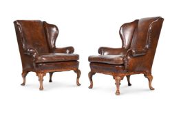 A PAIR OF WALNUT AND LEATHER UPHOLSTERED WING ARMCHAIRS, IN EARLY 18TH CENTURY STYLE