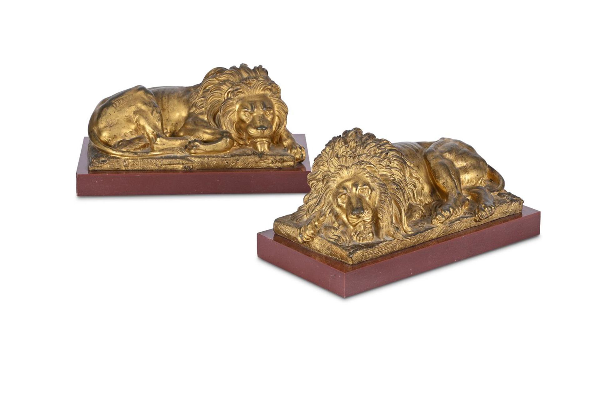 A PAIR OF GILT METAL FIGURES OF RECUMBENT LIONS, 19TH CENTURY