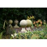 A SET OF FOUR COMPOSITION STONE SPHERE FINIALS ON BASES, 20TH CENTURY