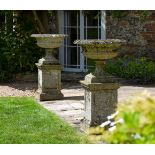 A PAIR OF STONE COMPOSITION VASES ON PLINTHS, EARLY 20TH CENTURY