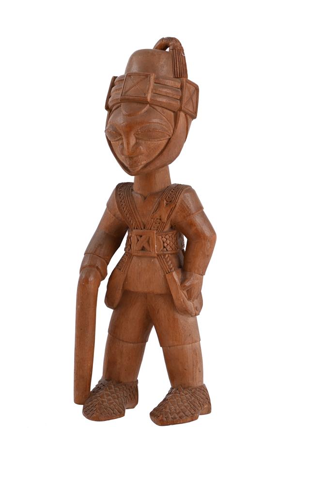 A YORUBA COLONIAL CARVED WOOD FIGURE OF A SOLDIER