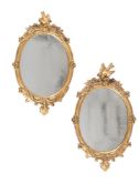 A PAIR OF CARVED GILTWOOD OVAL WALL MIRRORS