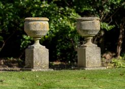A PAIR OF COTSWOLD STONE URNS ON PLINTHS, LATE 19TH OR 20TH CENTURY
