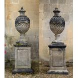 A PAIR OF STONE COMPOSITION 'POPE'S URNS' ON PEDESTALS, IN THE MANNER OF WILLIAM KENT