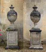 A PAIR OF STONE COMPOSITION 'POPE'S URNS' ON PEDESTALS, IN THE MANNER OF WILLIAM KENT