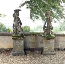 A PAIR OF STONE COMPOSITION FIGURES ON PLINTHS IN THE MANNER OF AUSTIN & SEELEY, 20TH CENTURY