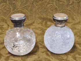 A pair of cut glass silver topped globular topped scent bottles standing 10cm tall
