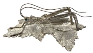 Modern silver model of a Grasshopper perched on leaves