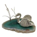 Modern silver model of a Swan swimming on a stylized agate slice pond amongst Bulrush