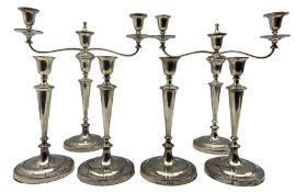 Set of four Edwardian silver candlesticks and pair of matching three light candelabra with tapering