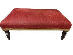 Rectangular low footstool upholstered in red fabric and raised on turned tapering supports