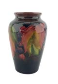William Moorcroft baluster vase decorated with leaf and berry pattern on a shaded ground