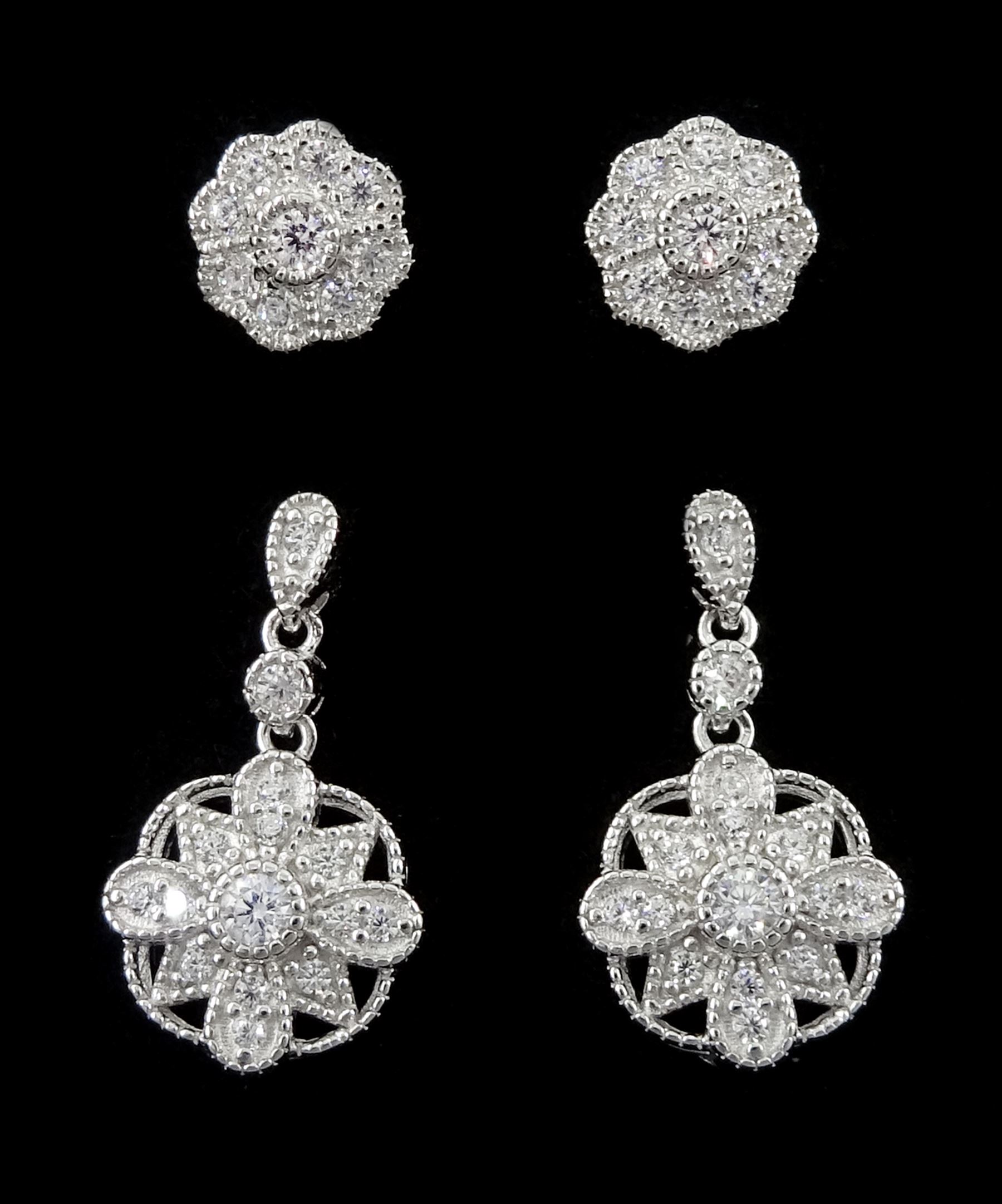 Pair of silver cubic zirconia flower cluster pendant earrings and a similar pair of stud earrings