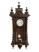 Late 19th century German 8-day striking wall clock in a mahogany case - pediment with carved decora