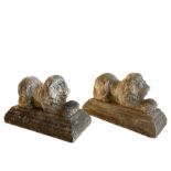 Pair of cast stone garden figures in the form of recumbent lions holding balls between their paws
