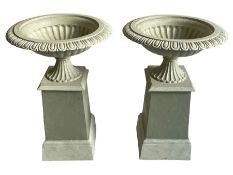 Pair of cast iron two-piece garden urns on plinths