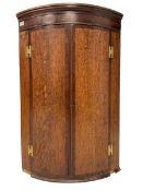 Early 19th century oak and mahogany banded bow-front corner cupboard