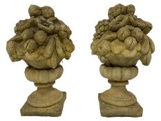 Pair of composite stone garden ornaments in the form of urns filled with fruit