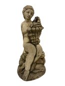 Composite stone garden ornament or water feature in the form of a nude maiden seated on rocks
