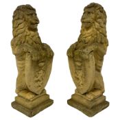 Pair of composite stone garden ornaments in the form of lions holding heraldic shields
