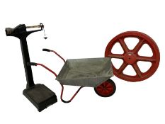 Wooden wheel foundry form or mould (D85cm); metal wheelbarrow; and a floor scale in black finish (H9