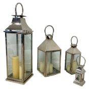 Four polished metal and glazed lanterns with candles