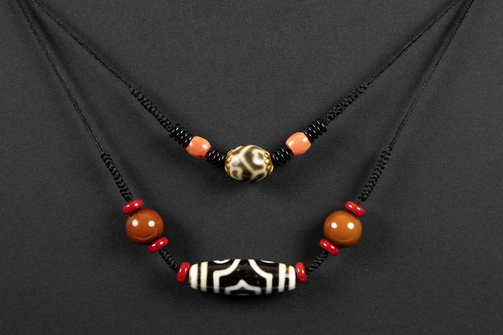 two Himalayan necklaces each with a dzi stone||Lot van twee colliers uit de Himalaya-gebieden