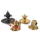 four inkwells in brass, one depicting the head of a monk