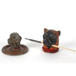 two inkwells, each with a dog's head - one in wood and one in metal
