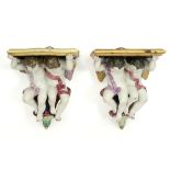 pair of Italian wall hanging consoles, each with two cupids, in polychromed ceramic