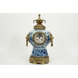 19th Cent. clock with an 18th Cent. Delft ceramic vase with blue-white decor and with mountings in g