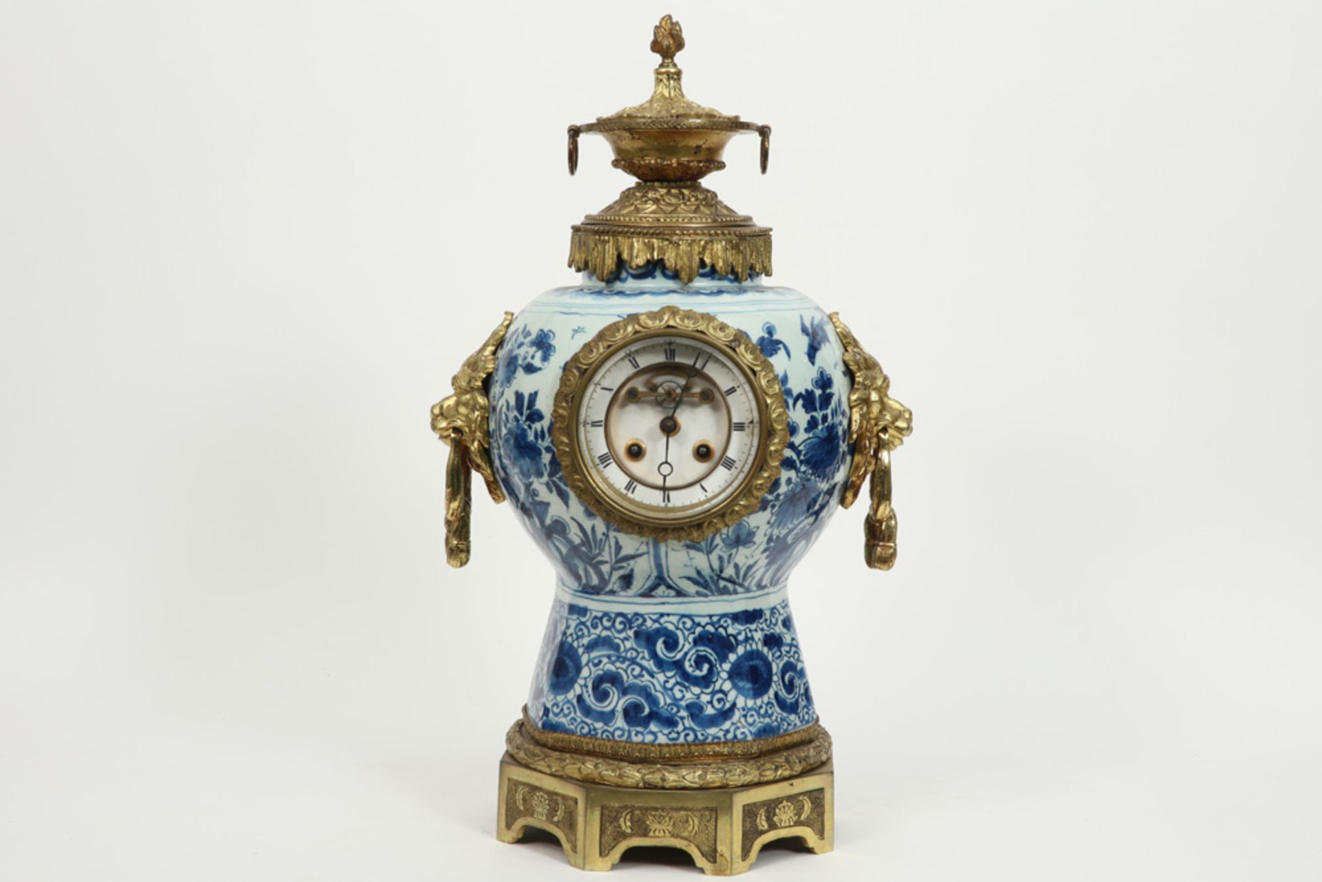 19th Cent. clock with an 18th Cent. Delft ceramic vase with blue-white decor and with mountings in g