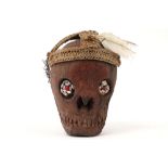 Indonesian Irian Jaya substitution skull in wood with inlaid eyes and headdress in natural fibers