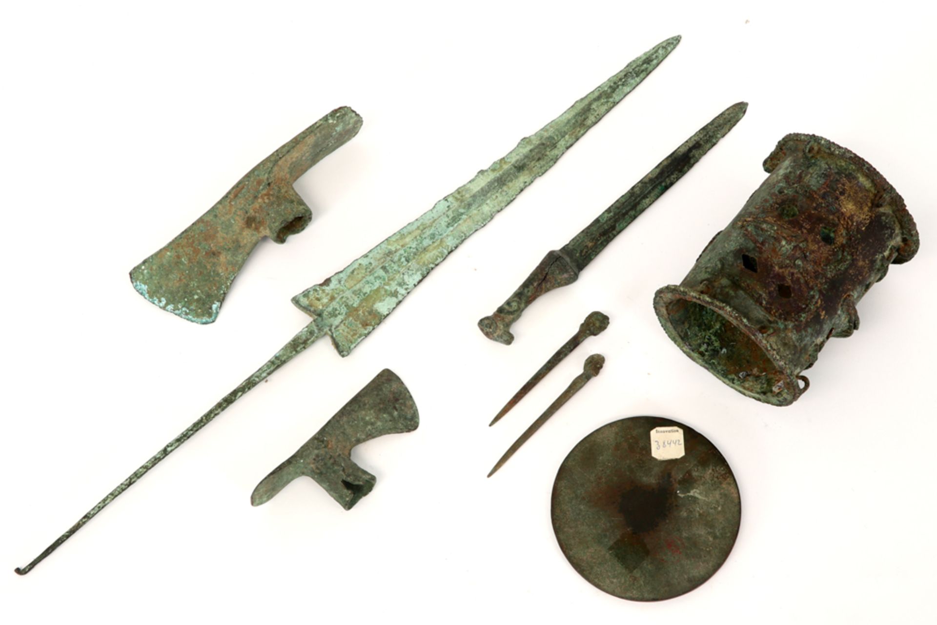eight archaeological finds in bronze with typical irisation amongst which an axe, a spear and hair