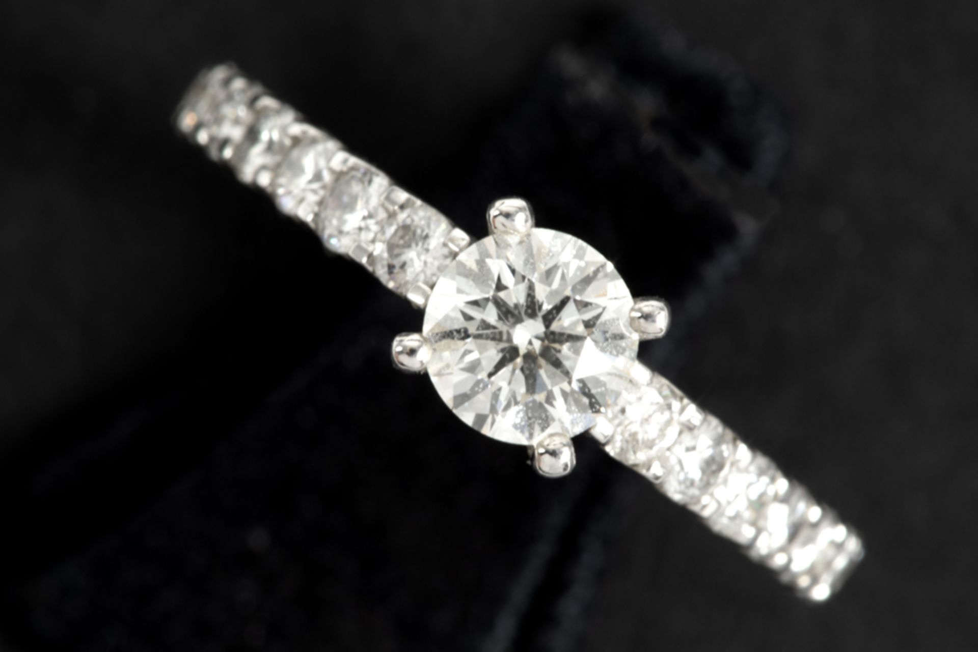 a 0,60 carat quality brilliant cut diamond set in a ring in white gold (18 carat) with ca 1 carat of
