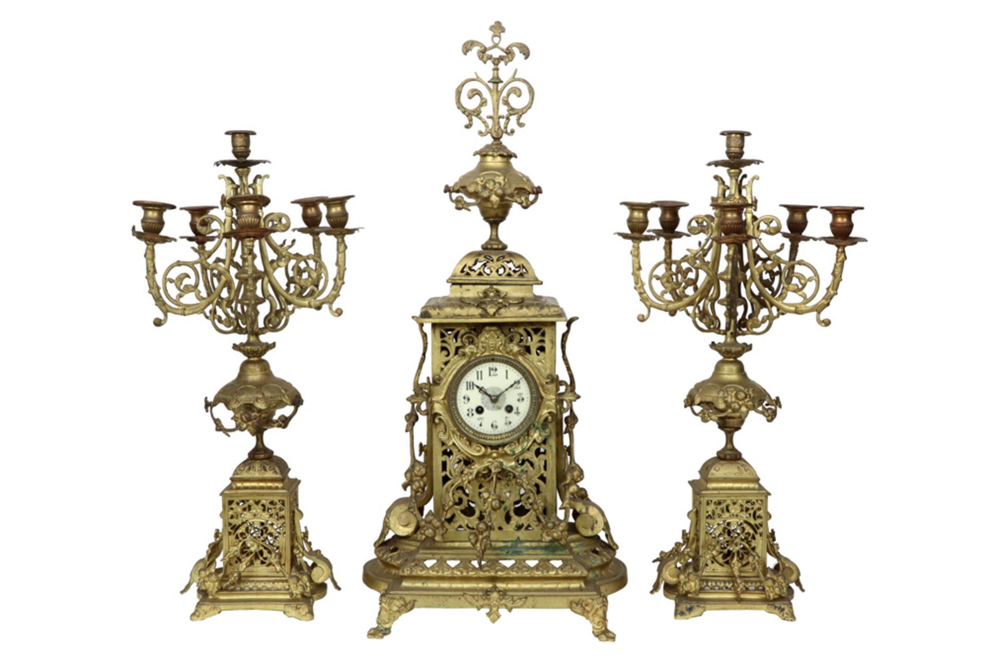antique brass garniture with a pair of candelabra and a clock || Antieke driedelige