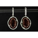 pair of trendy earrings in white gold (18 carat), each with a half geode of white and rust colored