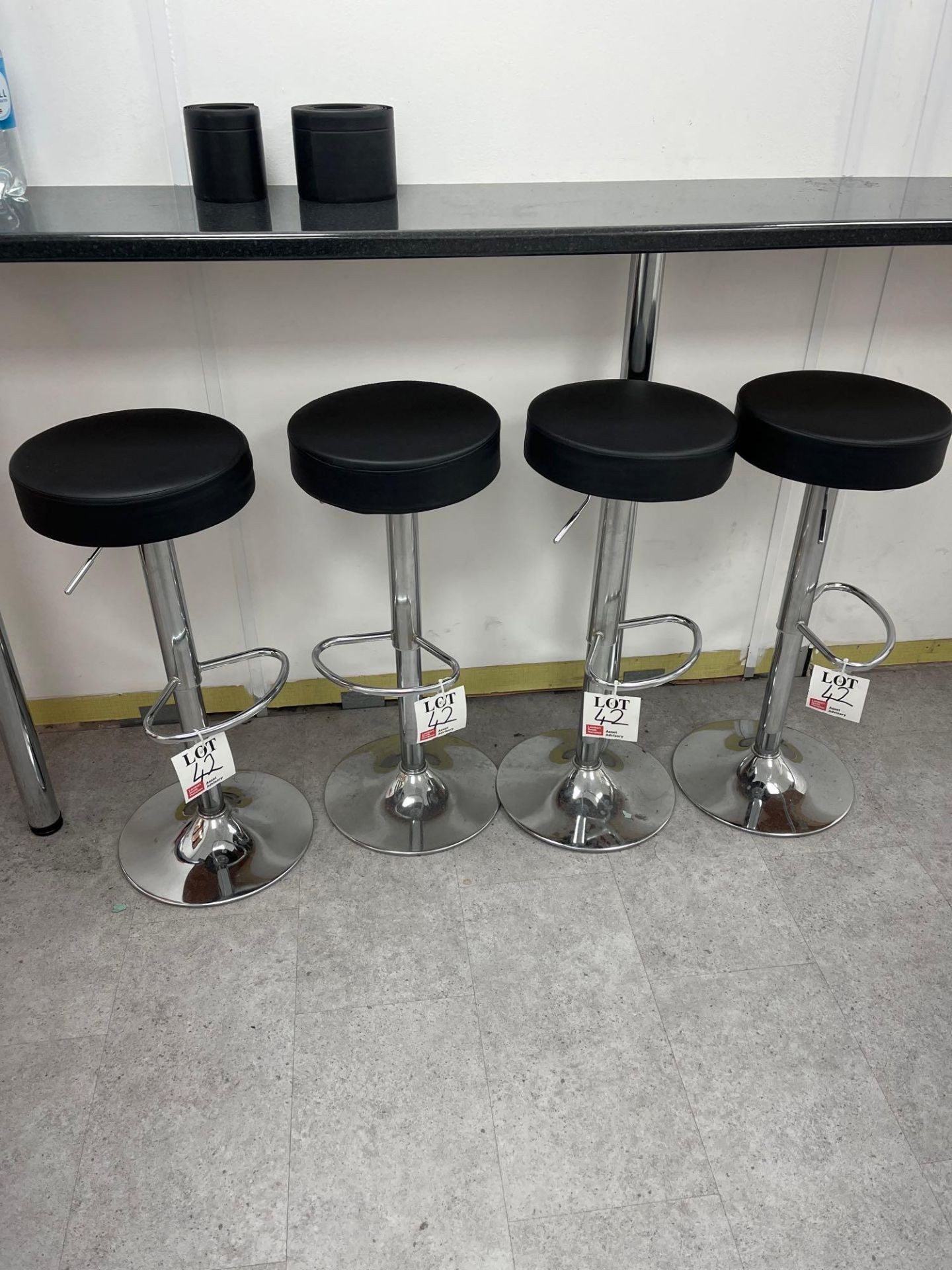 Four black leatherette circular stools with chrome base