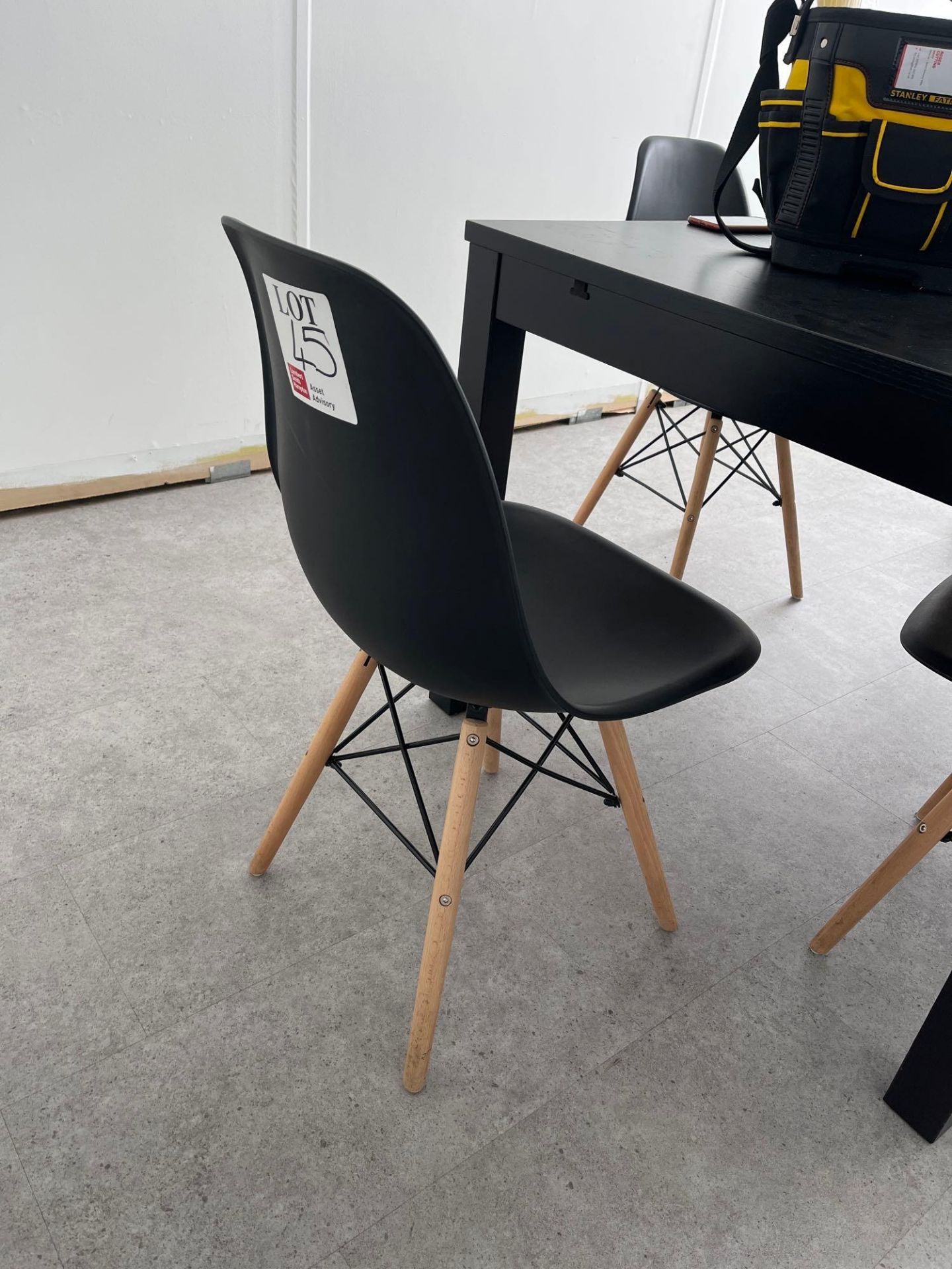 Four black plastic dining chairs with light wood legs