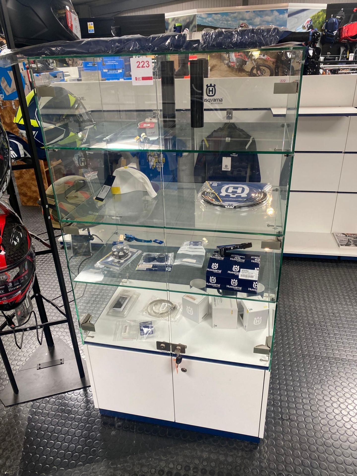 Glass display unit and contents to include various Husqvarna motorcycle spares and accessories