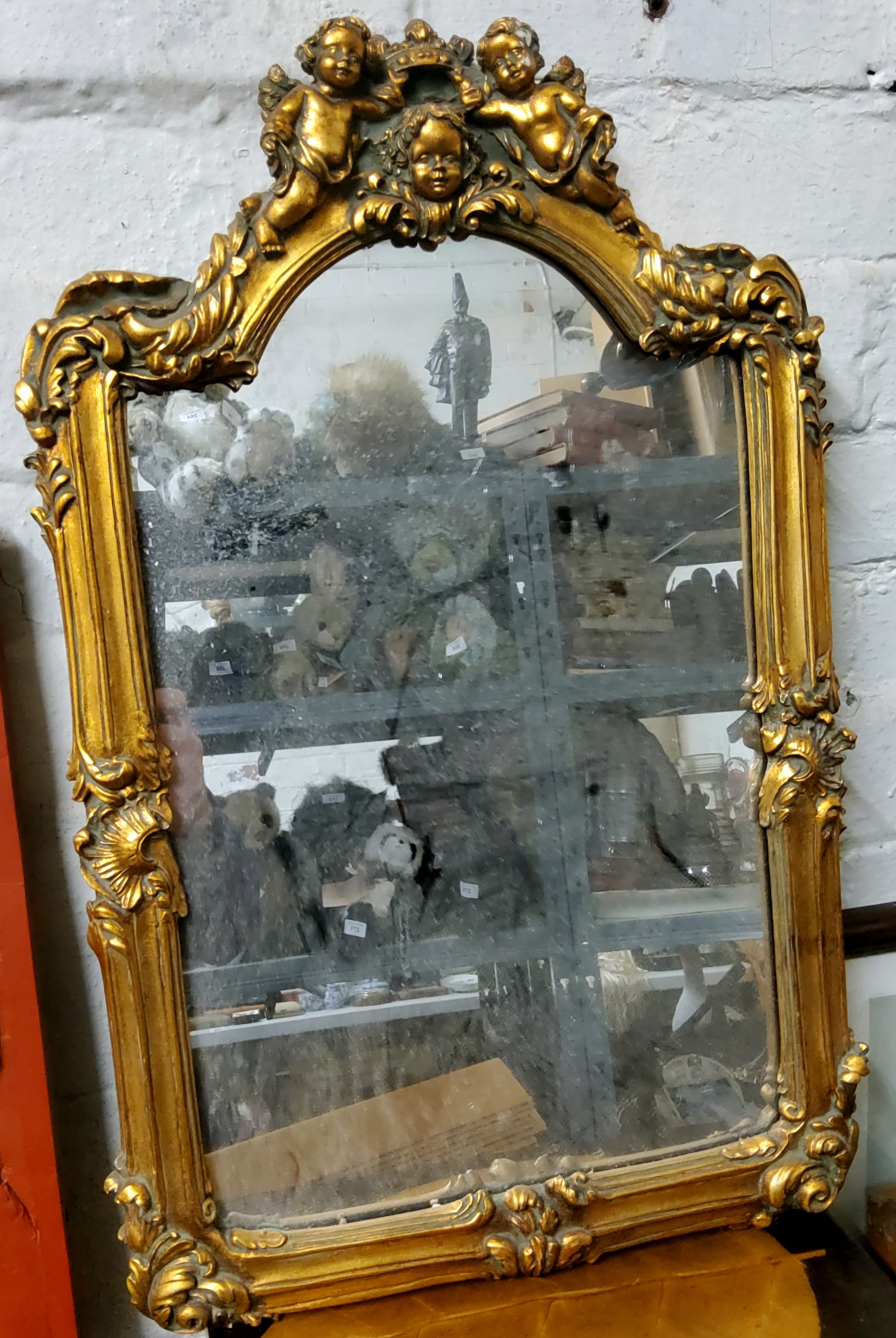 A decorative country house hall mirror / looking glass, surmounted with putti holding a crown with