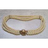 A three-strand cultured pearl choker, 9ct gold circular clasp mounted with a central pearl,