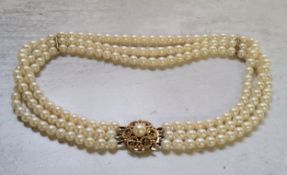 A three-strand cultured pearl choker, 9ct gold circular clasp mounted with a central pearl,