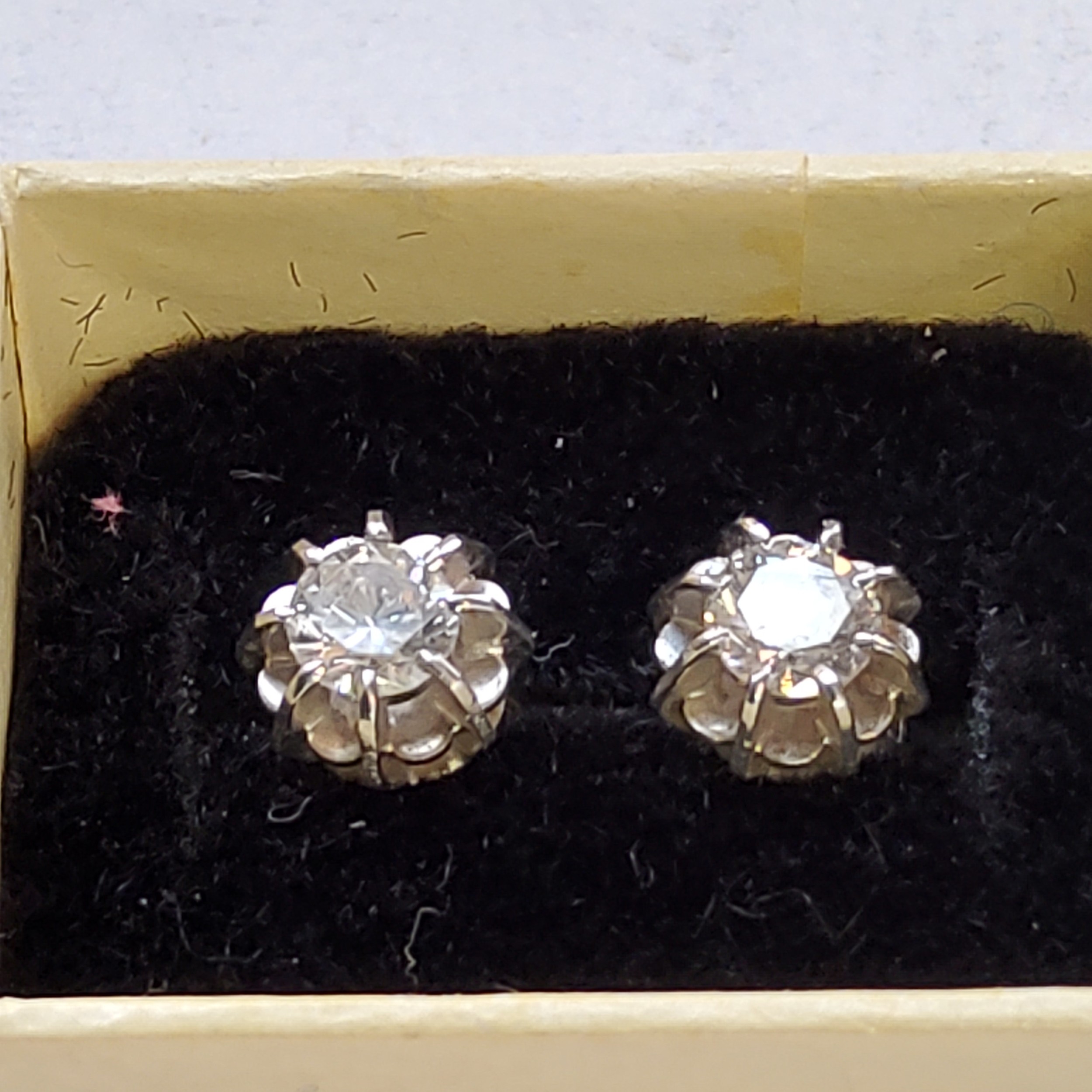 A pair of white metal diamond earrings each set with an approx. 0.25ct round diamond, backs