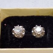 A pair of white metal diamond earrings each set with an approx. 0.25ct round diamond, backs