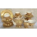 An Art Deco Tuscan tea service for six, decorated with an intricate gold filigree pattern on a white