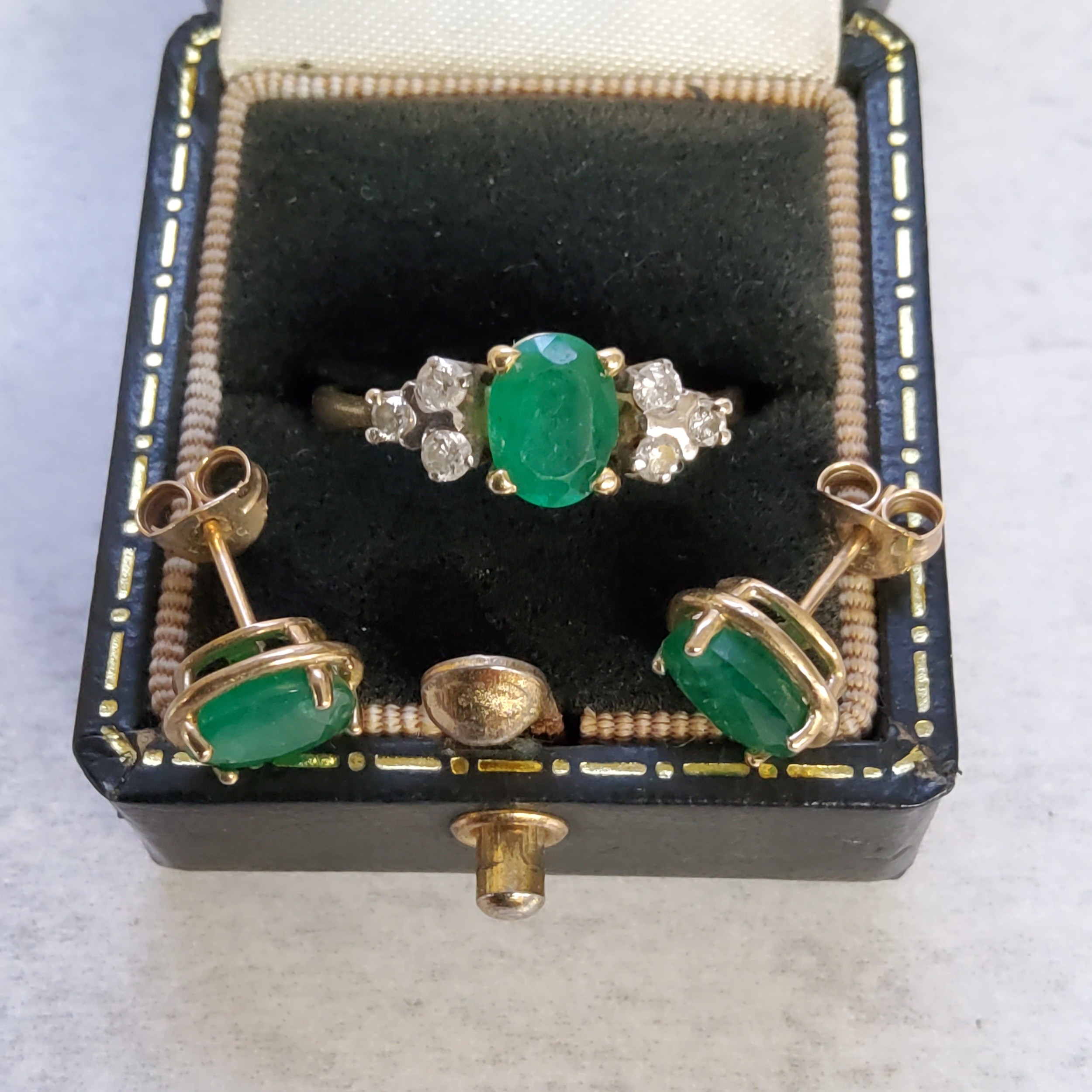 An 18ct gold ring claw set with a central oval emerald, flanked each side by three claw set round