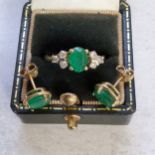 An 18ct gold ring claw set with a central oval emerald, flanked each side by three claw set round
