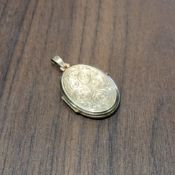 A 9ct gold oval locket, scroll decoration to front, 3.24g gross